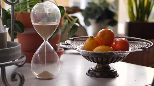 Sand Timer Next to Silver Fruit Bowl