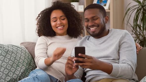 Happy Couple Relaxing at Home with Smartphone