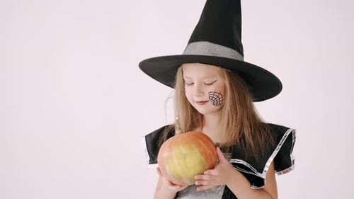 Girl in Witch Costume Holding Pumpkin