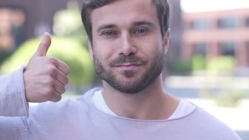Handsome Man Giving Thumbs Up in Urban Setting