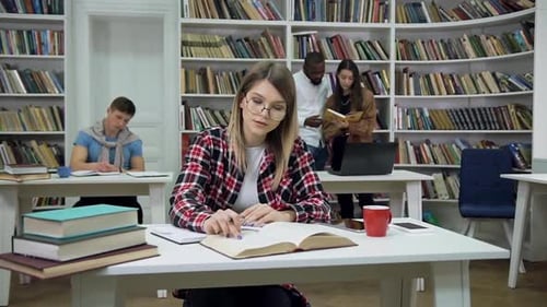 Young Female Student which Sitting in the Library, Reading Book