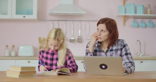 Preteen School Girl Making Homework and Mother Typing on Laptop. Family Stays at Home Together
