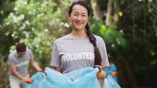 Cheerful Volunteer Holding Trash Bag in Park