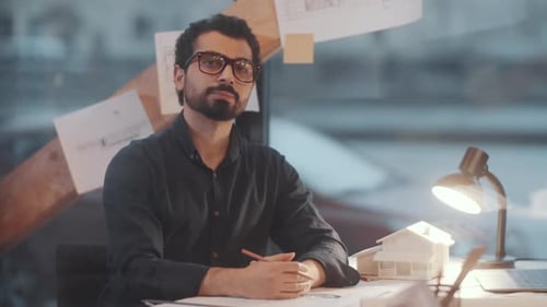 Thoughtful Architect Working on Plans in Bright Office
