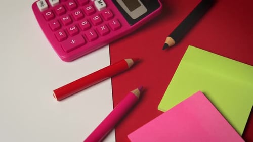 White Paper and Calculator and Crayons on a Red Desk