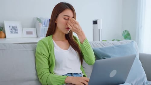 Young Woman Experiencing Fatigue While Working on Laptop