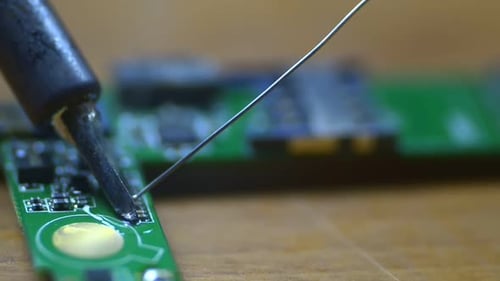 Technician Engineer in Workshop. Repairman Is Soldering Circuit Board of Electronic Device on Table