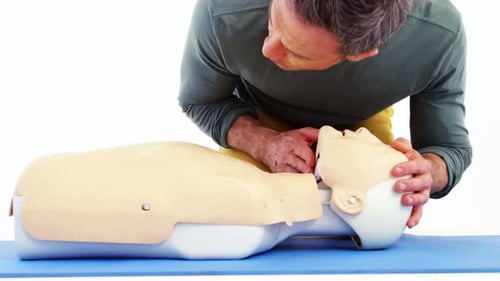 Man Practicing CPR on Mannequin for Training