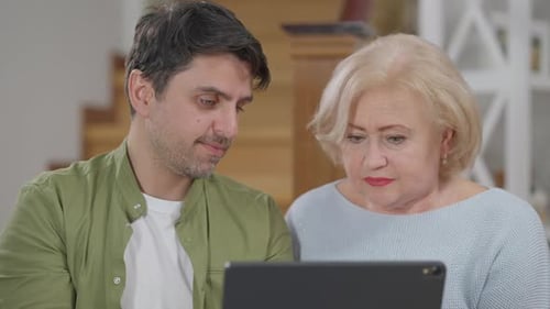 Man and Senior Woman Using Tablet Device at Home