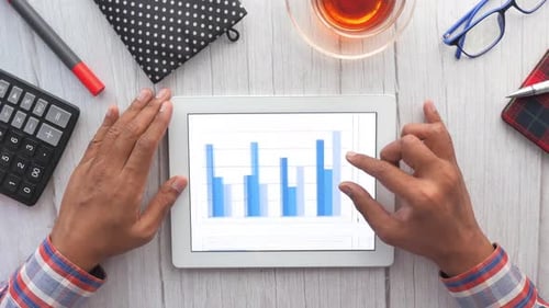 Man's Hand Working on Digital Tablet at Office Desk, Using Self Created Chart