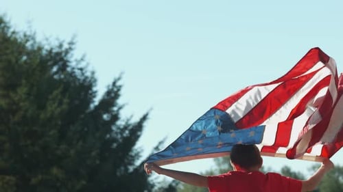Child Holding American Flag Waving in Wind Outdoors