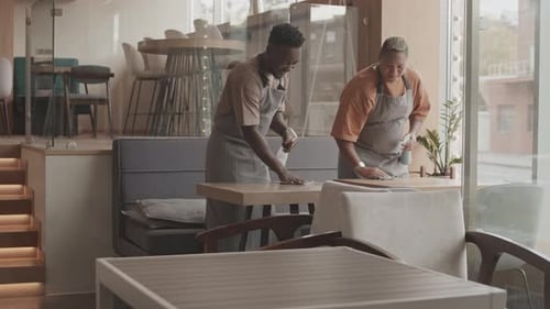 Cafe Staff Cleaning Tables Before Opening