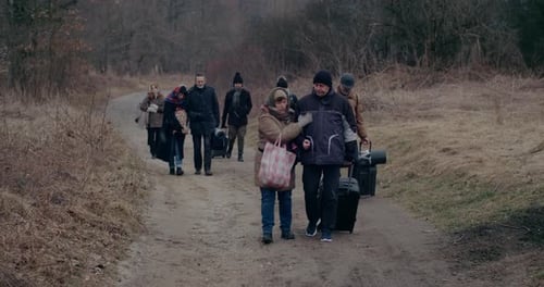 War Immigrants Walking With Luggage On Road During Snowfall