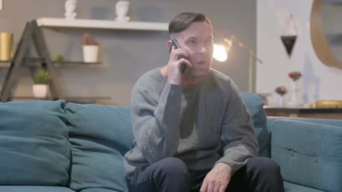 Man Sitting on Couch Talking on Phone