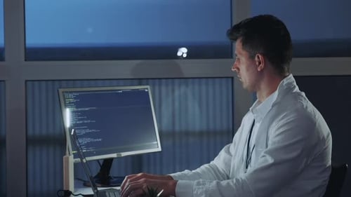 Seitenansicht eines jungen Elektronikingenieurs, der sich mit seiner Computerforschung beschäftigt