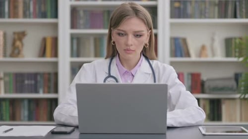 Lady Doctor Smiling at Camera While Using Laptop in Clinic
