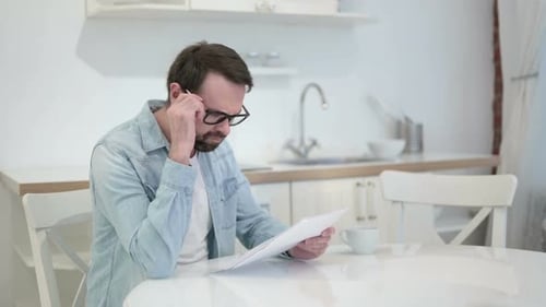 Stressed Man Reads Bad News in Kitchen