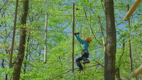 Young Adult Crossing Rope Bridge Course in Forest