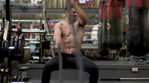 Shirtless Man Doing Intense Rope Workout in Gym