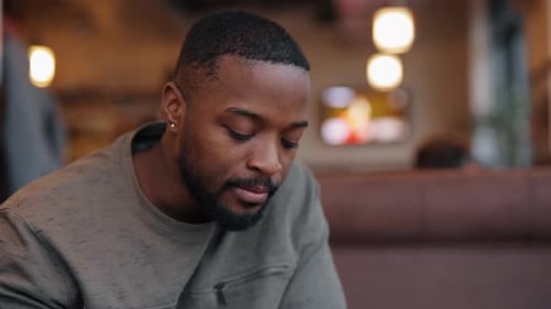 Thoughtful and Sad African American Man Drinking Tea Sitting in a Cafe