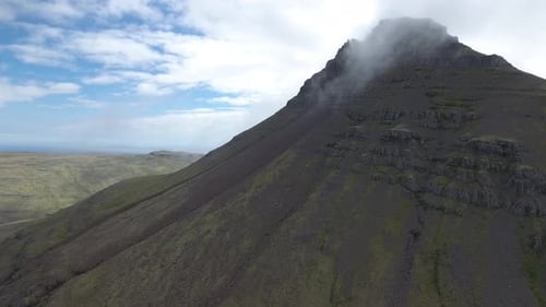 Wunderschöne Landschaft in Island - ein Berg mit seiner Spitze in der Wolke
