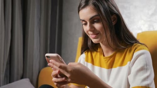 Young Woman Using Smartphone Device in Cozy Home