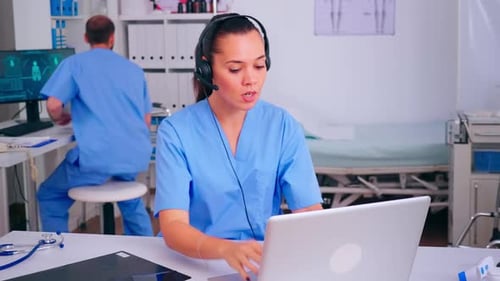 Medical Professional Working on Laptop with Headset On