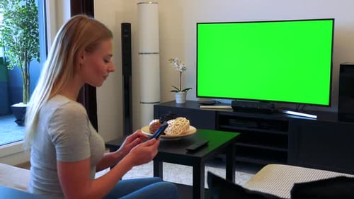 Woman Sits on Couch in Living Room and Works on Smartphone - TV Green Screen