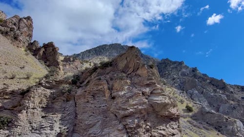 View of a jagged mountain peak then flying backwards to reveal the rugged terrain of cliffs, peaks a