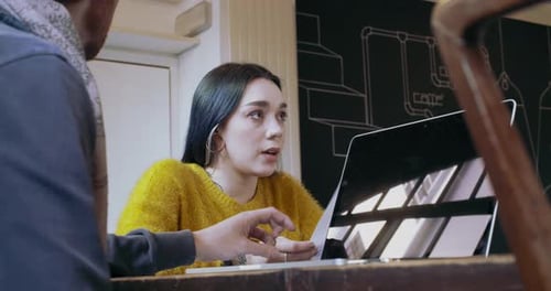 Two Young People Working Together with Laptop at Restaurant or Coworking