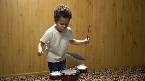 Young Child Playing Toy Drum Set at Home