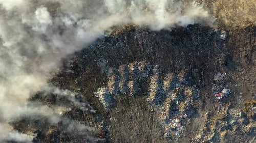Aerial view of burning garbage pile in trash dump or landfill
