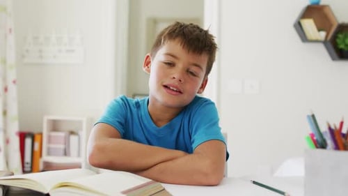 Smiling Boy with Books and Pencils at Table