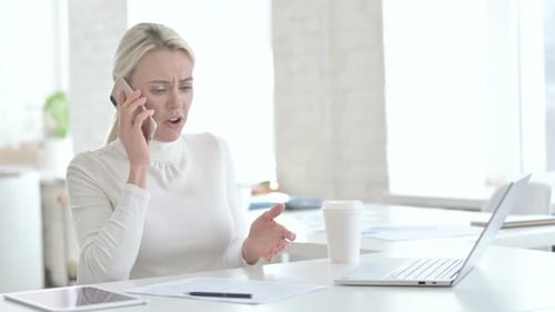 Worried Woman Talking on Phone at Desk