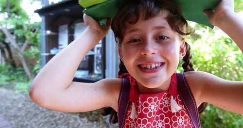 Portrait of schoolgirl carrying books overhead at school