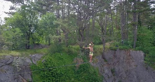 Man Balances on Tightrope in Wild Forest