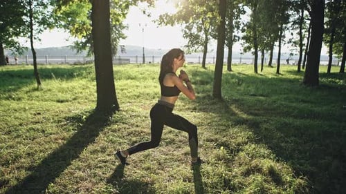 A Sports Girl Performs Fitness Exercises on the Hips. Summer Green Park on the Background