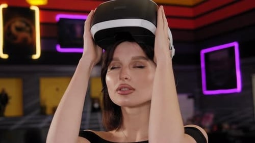 A Young Woman Puts on Virtual Reality Glasses for a Video Game in a Game Room