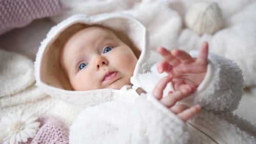 Adorable Infant Lying on Soft White Blanket