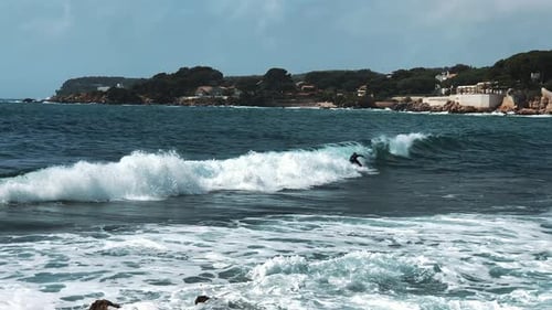 One Surfer Riding, Turning with Spray on Blue Ocean Wave and Crashing Into Other Surfer. Surfing