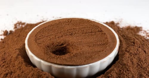 Nutmeg Dropping Into Bowl of Ground Spice