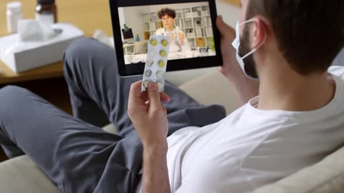 Man on Video Call with Doctor Showing Pills