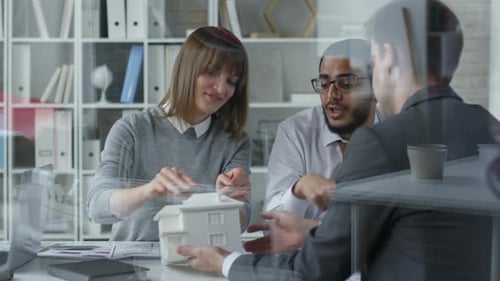 Team of Architects Discussing House Model in Office