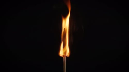 Isolierte Flamme brennt auf einem Streichholz auf schwarzem Hintergrund