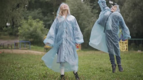 Wide Shot of Joyful Children Jumping and Catching Rain Drops with Mouth