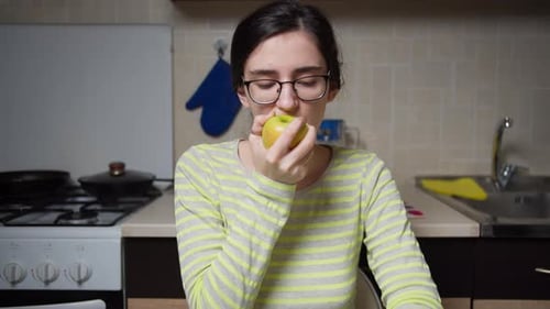 Woman Eating an Apple in Kitchen