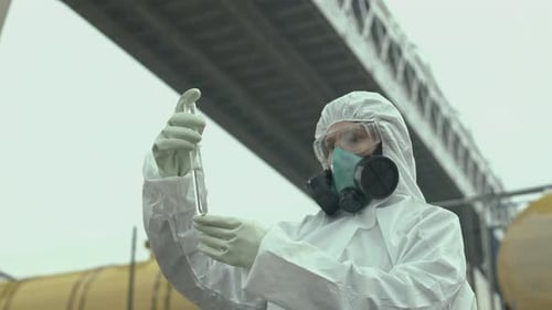 Scientist Examining Sample in Hazmat Suit Outdoors