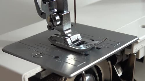 The needle of a sewing machine makes a thread stitch.