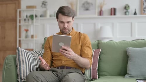Man With Tablet at Home Looking Confused