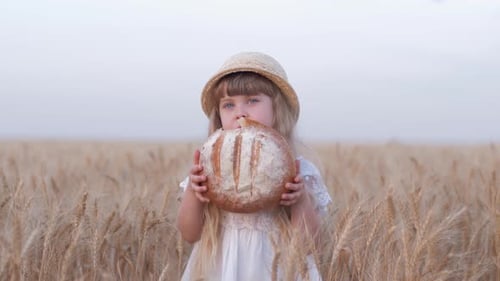 Happy Girl Eats Bread in Wheat Field